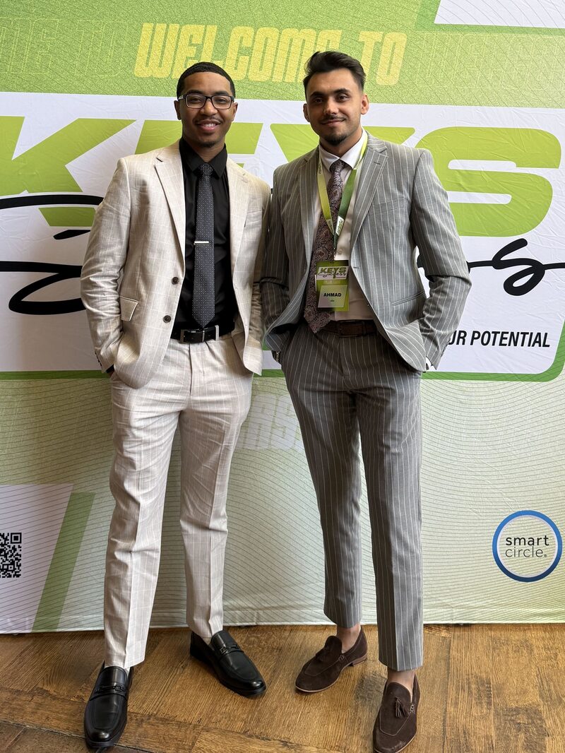Two Contrast Marketing Inc. team members at the KEYS conference welcome backdrop
